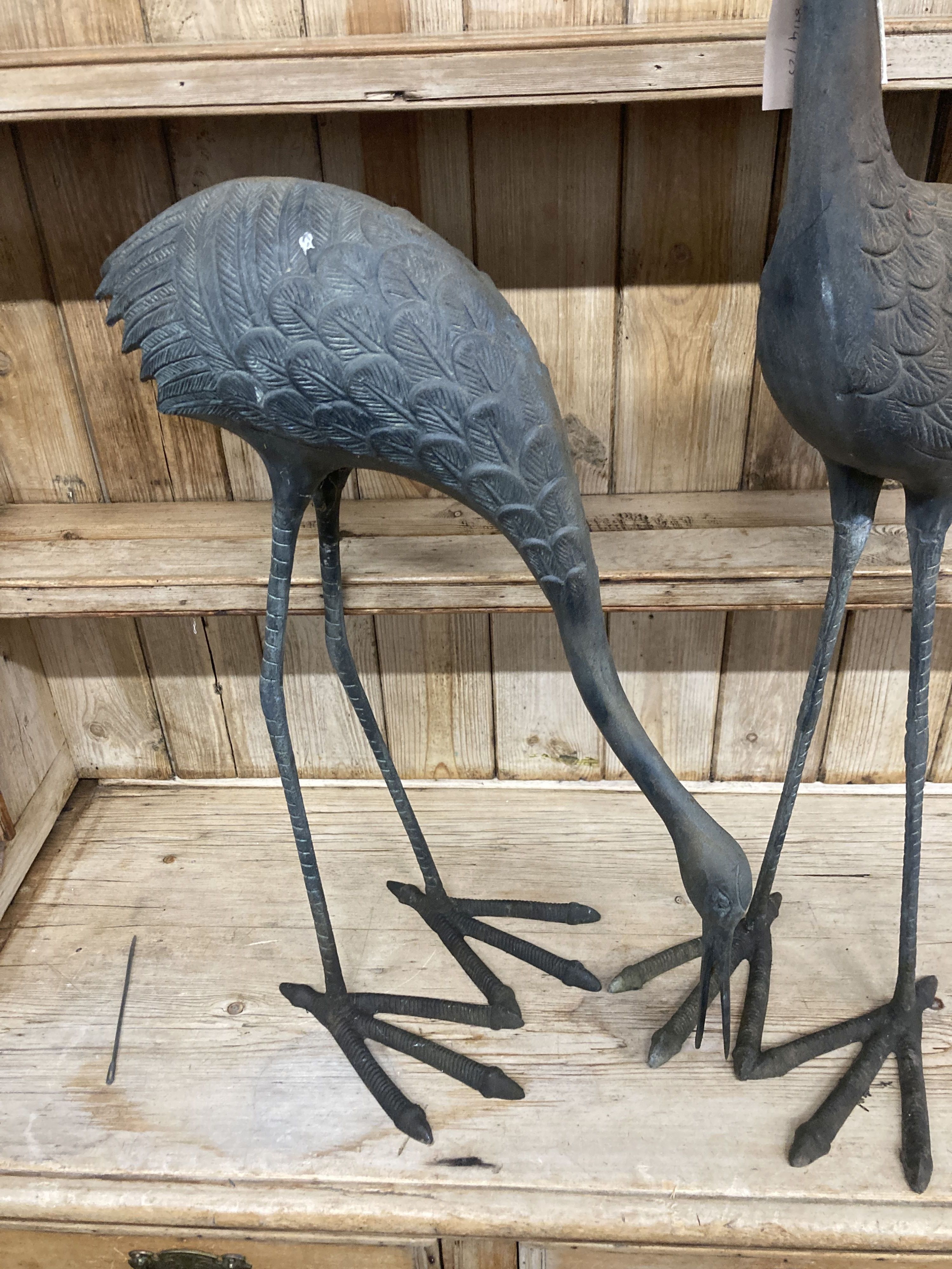 A pair of patinated cast metal garden cranes, larger 91cm high